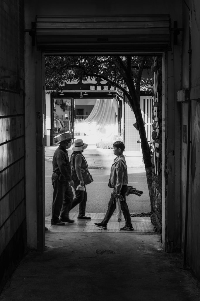 Monochrome image of pedestrians walking through a city gateway, capturing a candid urban moment.
